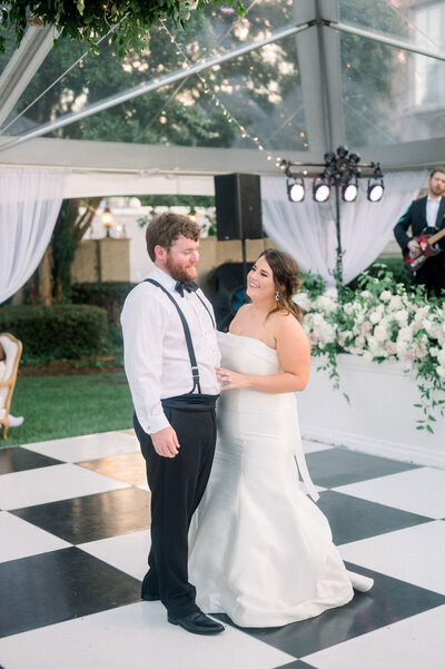 bride and groom smiling while standing on checkerboard floor