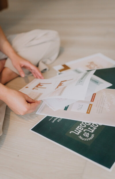 Hands sorting through Born to Roam papers laid out on the floor
