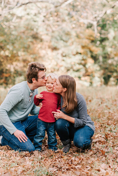 A toddler getting kisses from his parents in a fairfax county park