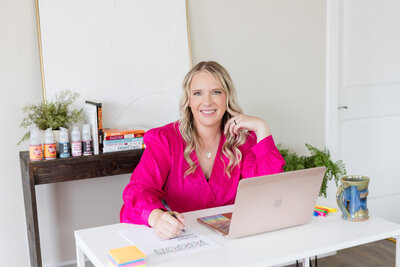 Becca sitting in her sunlit office in front of her computer