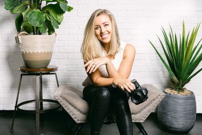 Cali Warner in Studio headshots holding camera with leather pants and plants