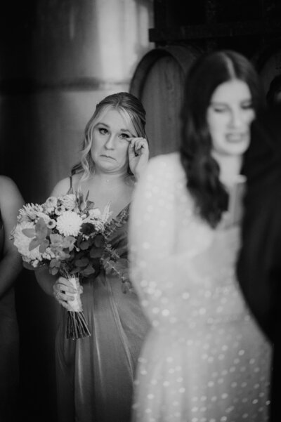 Bridesmaid wiping away tears as she watches her best friend get married