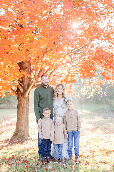 Family in neutral colors smiling at the camera on a cool fall morning in Dayton, Ohio at Wegerzyn Gardens Metropark.