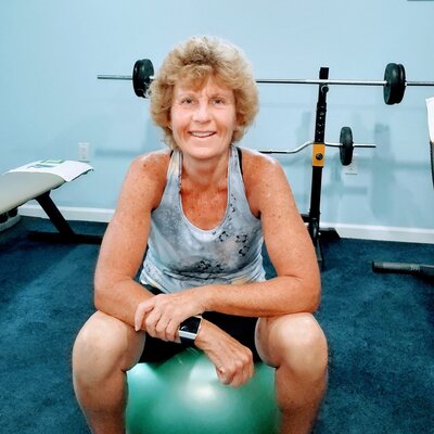 Coach Helen Ann sitting on a green exercise ball of an at-home workout