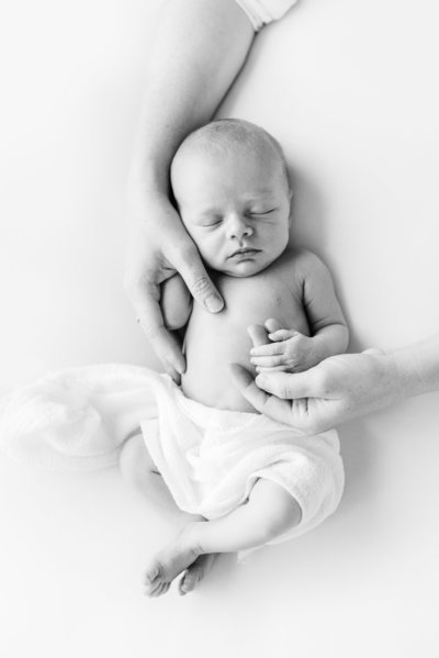 Newborn photography with mom's hands holding sleeping baby