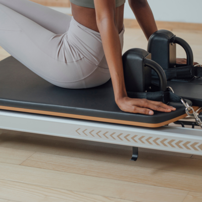 Another woman using a Pilates reformer, demonstrating full-body training at Jaz Pilates, with branding and social media management by Muse Studio.