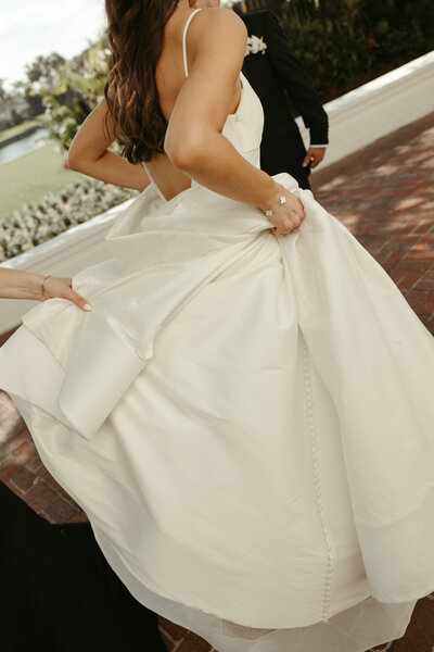 Bride adjusting her gown as she walks outdoors, a candid luxury wedding moment planned by The Eventful Gals in Northeast Florida.