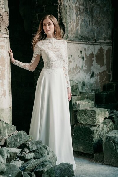 Inspired by timeless royal weddings, this A-line gown features a high neckline, lace sleeves and a soft crepe skirt.