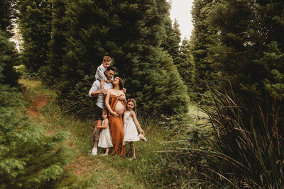 Family cuddle together amongst pine trees