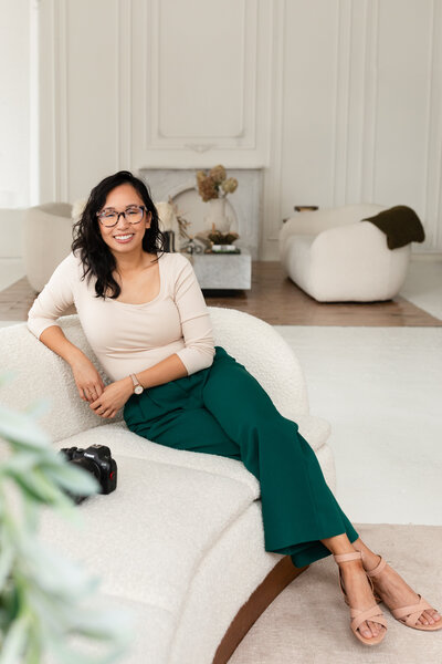 Portrait of Anh Nguyen, photographer behind Anh Point Photography, smiling at the camera while sitting on the couch.