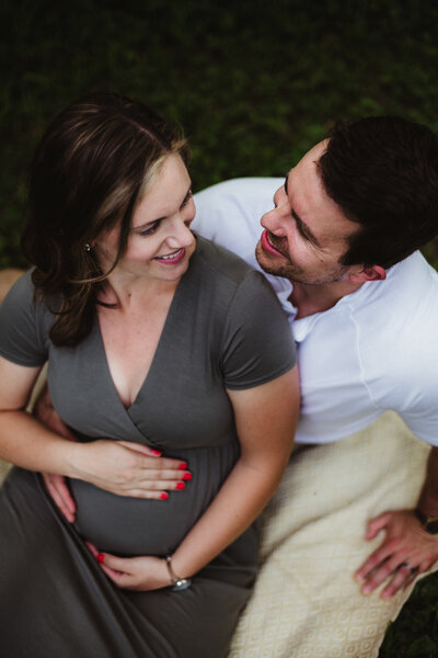 A pregnant woman and her husband sitting and smiling at each other