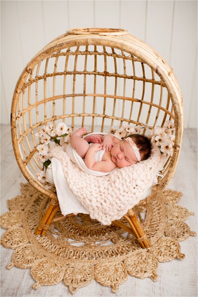 baby girl sleeping in wicker egg chair