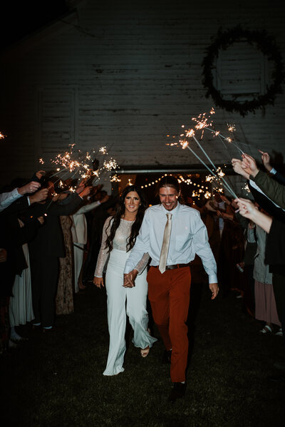 happy couple running under sparklers at their Wyoming wedding