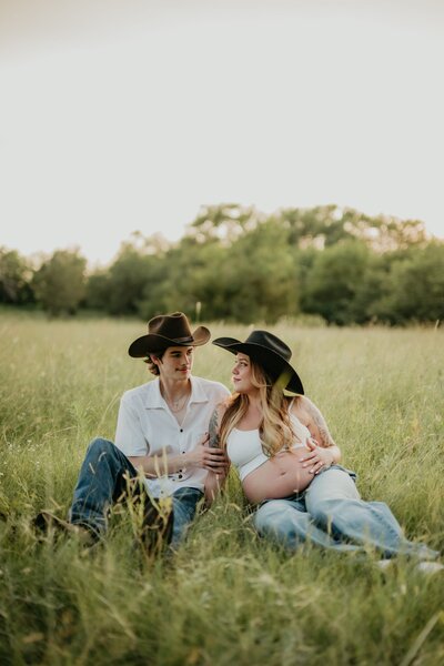 mom and dad with cowboy hats in field, country themed photo session, texas panhandle maternity photographer
