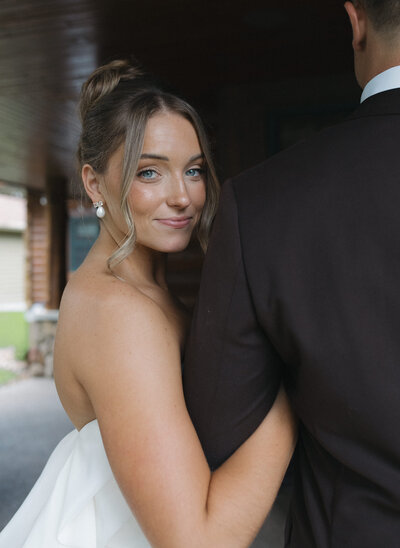 Bride smiling over grooms shoulder in couples portraits on their intimate wedding day in northern Minnesota.  Captured by a Minnesota Wedding and Elopement Photographer specializing in couples looking for an intimate, documentary style wedding day coverage. 
