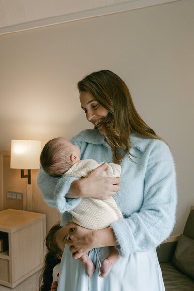 A mother holding her newborn, smiling at her baby boy