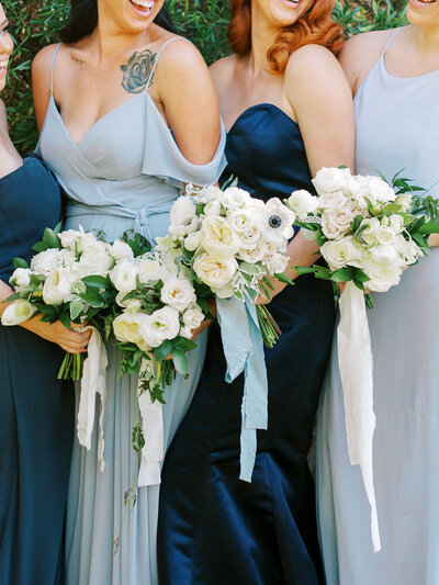 close up of bridesmaids in blue dresses holding flowers