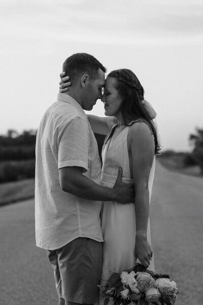 newly married couple standing close with their foreheads together in the middle of an empty road