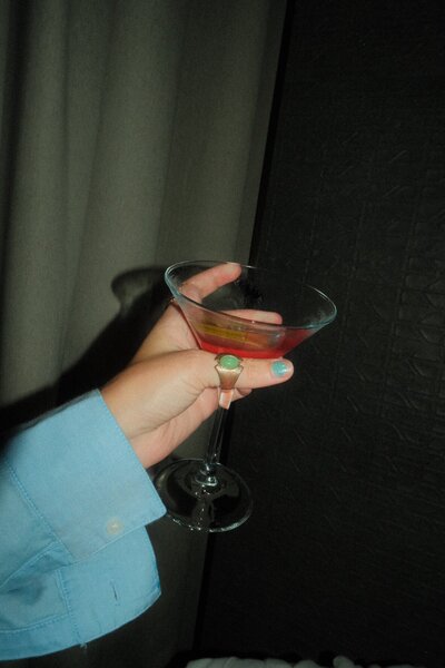 Flash photo of a hand holding a drink in a martini glass