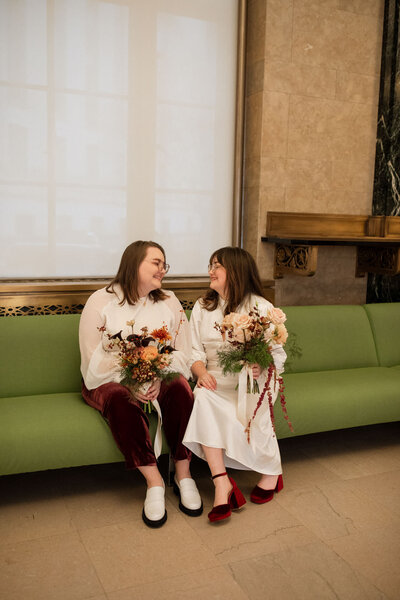nyc city hall couple with two bouquets and red velvet sitting on green couch