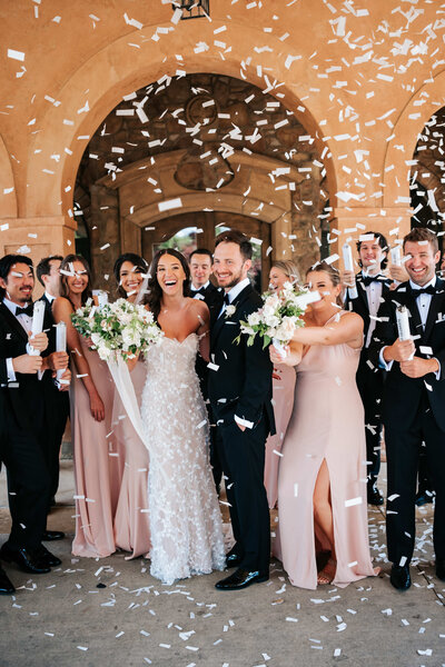 wedding party celebrates with flower petals after ceremony