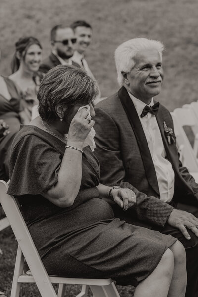 black and white candid photo of a mom and dad crying at a wedding ceremony