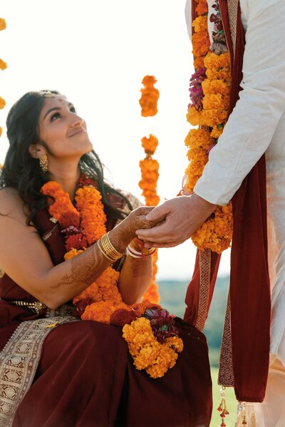 Indian wedding ceremony detail image of holding hands with orange garland of flowers