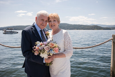 Groom helping bride step up onto a rock in the water in White Fish Montanta