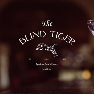 Luxury branding service for client, The Blind Tiger. An illustrated tiger logo in white with the words: "The Blind Tiger" circled above it in white font. The words: "speakeasy cocktail lounge + small bites " appears at the bottom half also in white font.