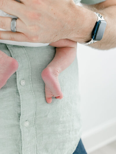 close up of dad holding newborn baby feet
