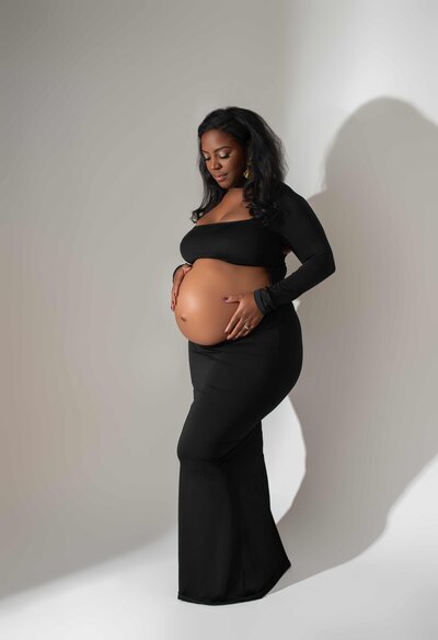 Los Angeles Luxury Maternity Photographer - Expecting Mom looking at belly in belly exposed black dress