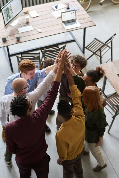 A diverse team high-fives after meeting huddle