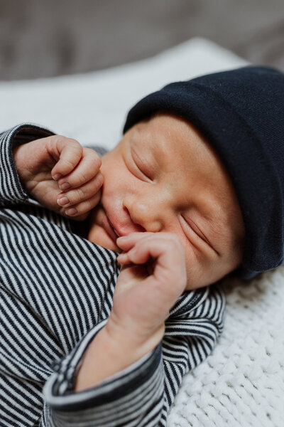 Newborn baby Oli sleeping with hands by his face for his newborn photoshoot.