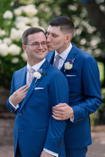 two grooms standing facing the same direction