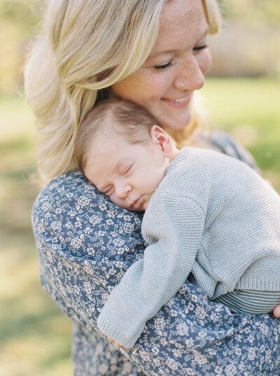 mother holding her new baby boy on her shoulder