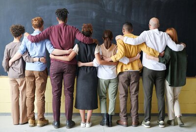 Image of a group of people with their arms around each others backs for support