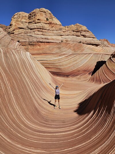 Aimee standing with her hands up in the airin front of the Wave