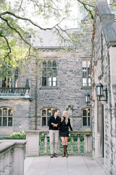 Couple walking hand in hand at Trinity College in Toronto, captured during romantic engagement photoshoot by local Toronto photographer