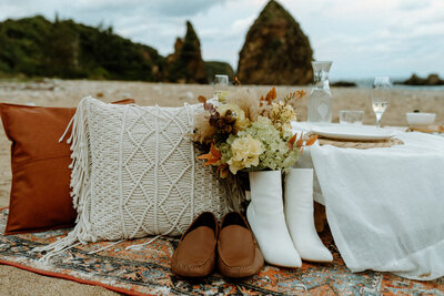 elopement table setup with pillows and shoes and bouquet on the beach