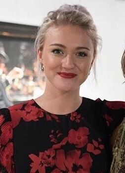 A lady smiling wearing black and red floral dress