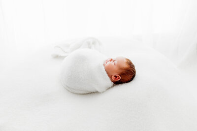 Newborn baby swaddled on white blanket
