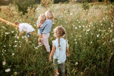 four children walking into flower field at sunset