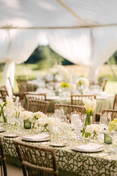 Wedding reception table with patterned green table cloth, and green accent vases