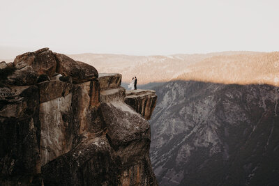 Bride and groom embrace at the edge of Taft Point, surrounded by cliffs and golden light during their intimate Yosemite elopement