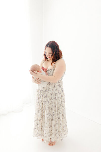 A mom holding her newborn baby while taking photos with Chelsea Nichole Photography in Grand Forks, North Dakota. 