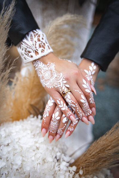 De bruid draagt witte henna, trouwjurk van de Bruidszaak in Purmerend en  leerjasje van Aim Your Weddings