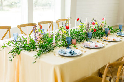 Tablescape with yellow tablecloth and colorful floral centerpieces