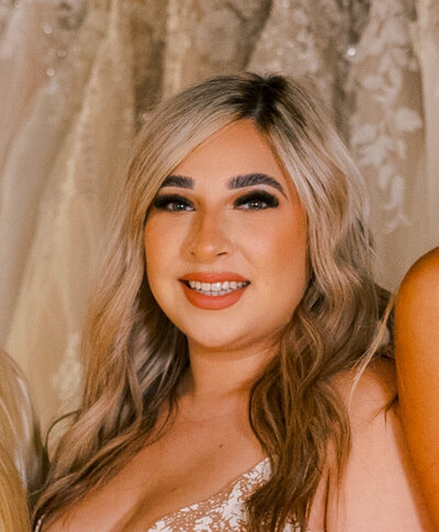 Bridal Stylist, Crysabel headshot in front of wedding dresses.
