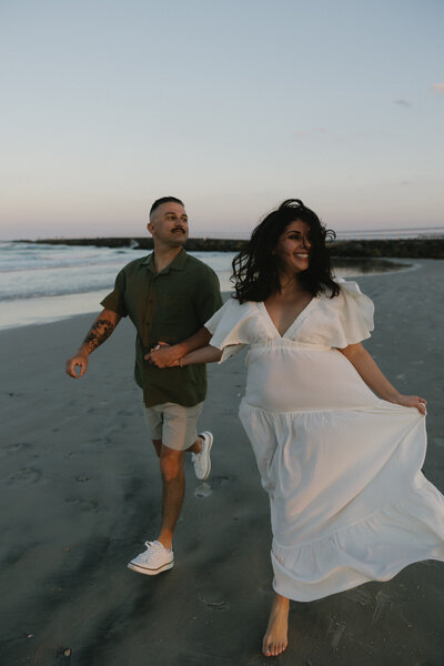 engagement session with couple running on the beach during blue hour.