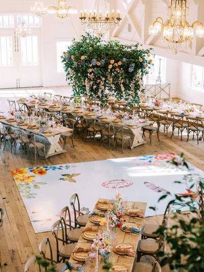 Large floral installation and painted dance floor at a Central Texas wedding venue, styled for a bold and unforgettable wedding floral arrangement